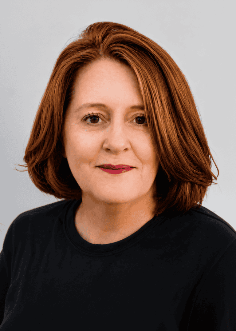 Portrait of a woman with red hair wearing a black shirt against a gray background. — friendsofgeorges.org