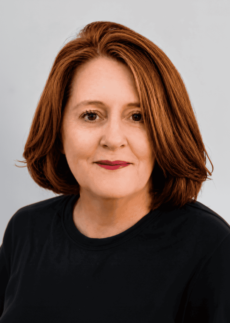 Portrait of a woman with red hair wearing a black shirt against a gray background. — friendsofgeorges.org