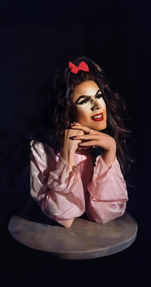 Performer in feathered gown strikes a pose under stage lights at Memphis show. — friendsofgeorges.org
