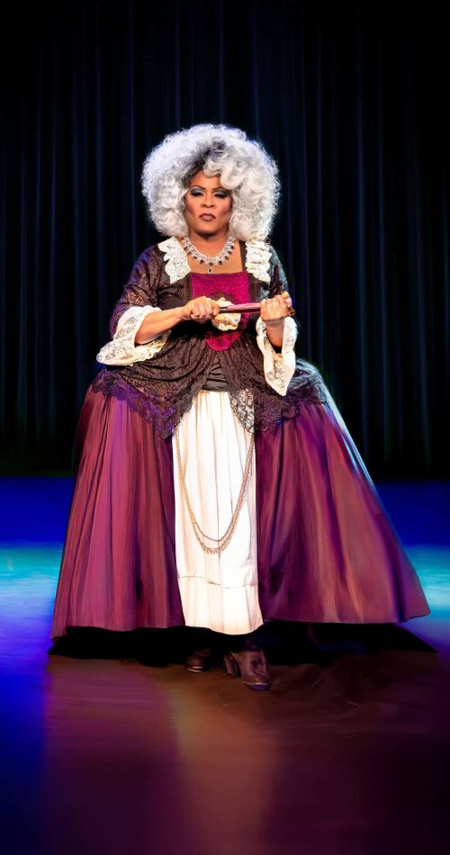Performer in feathered gown and white wig on stage at Evergreen Theatre. — friendsofgeorges.org
