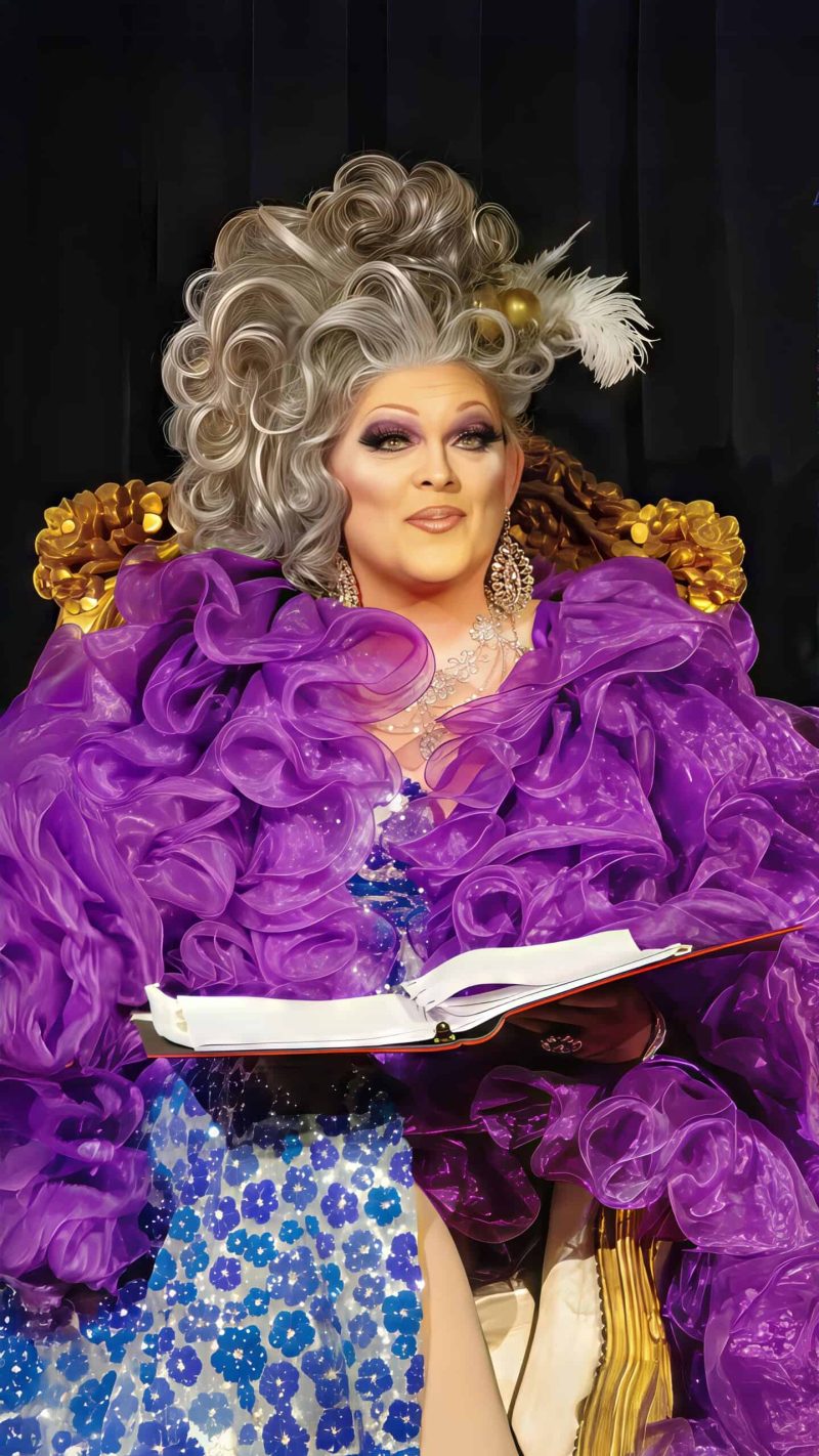 Allysun holds an open book in a purple feathered costume for Out in the Woods.